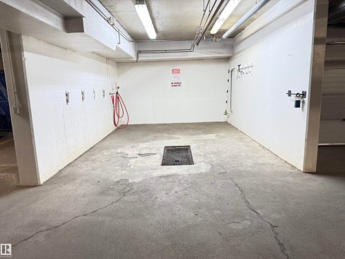 Utility space featuring concrete flooring, white block walls, overhead fluorescent lighting, and a central floor drain - #302 8215 84 Av Nw, Edmonton, AB - Indoor Photo Showing Garage