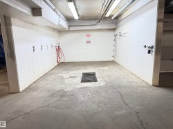Utility space featuring concrete flooring, white block walls, overhead fluorescent lighting, and a central floor drain - 