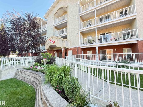 Multi-story residential building featuring light-toned stucco and brick siding - #302 8215 84 Av Nw, Edmonton, AB - Outdoor With Balcony With Exterior