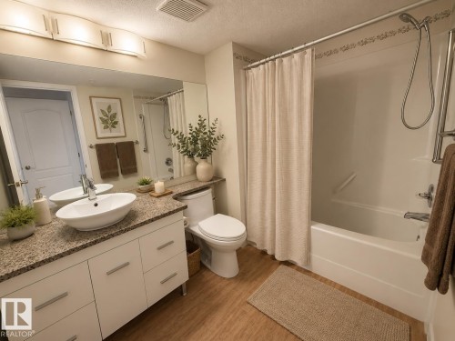 Bathroom featuring a white floating vanity with a granite-style countertop, a vessel sink, and chrome fixtures - #302 8215 84 Av Nw, Edmonton, AB - Indoor Photo Showing Bathroom