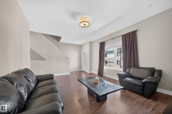 Spacious living area featuring wood-finish flooring, neutral wall tones, a large window, and recessed lighting - 