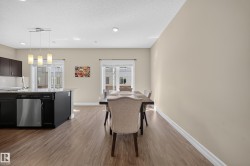Open-concept kitchen and dining area featuring wood-finish flooring, dark cabinetry, and light-toned walls - 