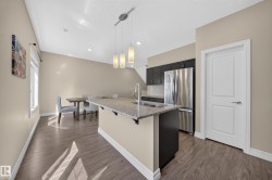 Kitchen island with a light-toned countertop, under-mount sink, and contemporary pendant lighting - 