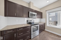 Kitchen featuring dark wood cabinetry, light-toned countertops, white subway tile backsplash, and stainless steel appliances - 