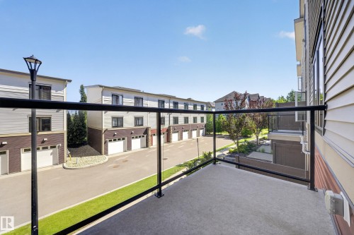 Balcony featuring a glass railing and concrete flooring - #100 804 Welsh Dr Sw, Edmonton, AB - Outdoor With Balcony With Exterior