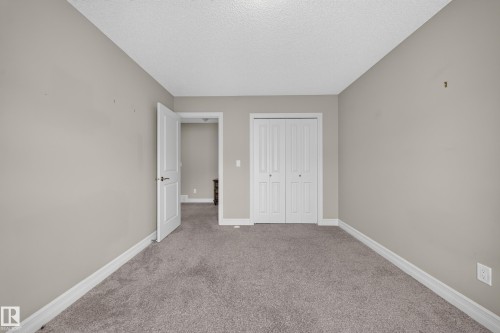 Carpeted interior room with neutral-toned walls, white baseboards, and a white ceiling - #100 804 Welsh Dr Sw, Edmonton, AB - Indoor Photo Showing Other Room