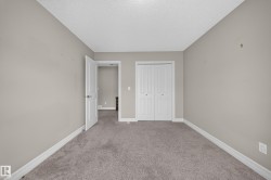 Carpeted interior room with neutral-toned walls, white baseboards, and a white ceiling - 