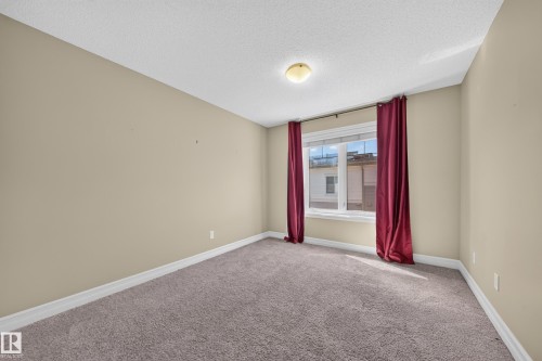 Neutral-toned room with plush carpet flooring and a single window - #100 804 Welsh Dr Sw, Edmonton, AB - Indoor