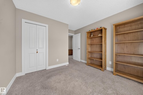 Neutral-toned room featuring a light brown carpet, white baseboards, and a white ceiling with a flush-mount light fixture - #100 804 Welsh Dr Sw, Edmonton, AB - Indoor