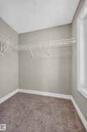 Walk-in closet featuring wire shelving, wall-to-wall carpeting, and a window with white trim - 