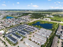 Aerial perspective showcasing a modern townhome community with uniform architecture and dark-pitched roofs - 