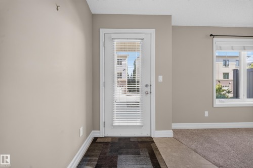 Entryway with a full-light door featuring internal blinds, wood-finish flooring, and light neutral wall tones - #100 804 Welsh Dr Sw, Edmonton, AB - Indoor Photo Showing Other Room
