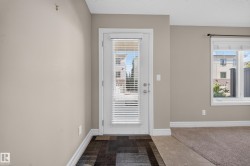 Entryway with a full-light door featuring internal blinds, wood-finish flooring, and light neutral wall tones - 