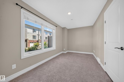 Neutral-toned room featuring a large window, recessed lighting, and soft carpet flooring - #100 804 Welsh Dr Sw, Edmonton, AB - Indoor Photo Showing Other Room