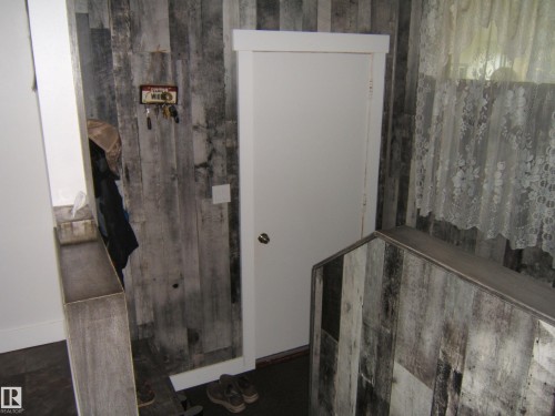 Distressed wood-finish plank walls complementing a white paneled door with polished hardware - 151042 Twp  Rd 562, Rural Two Hills County, AB - Indoor
