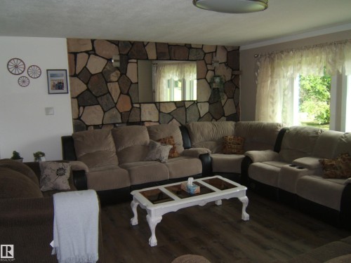Living area featuring a floor-to-ceiling stone-faced accent wall with an integrated mirror - 151042 Twp  Rd 562, Rural Two Hills County, AB - Indoor Photo Showing Living Room