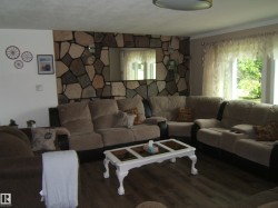 Living area featuring a floor-to-ceiling stone-faced accent wall with an integrated mirror - 