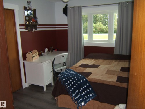 Space featuring contemporary wood-finish flooring, a white window frame, and a contrasting two-tone wall treatment - 151042 Twp  Rd 562, Rural Two Hills County, AB - Indoor Photo Showing Bedroom