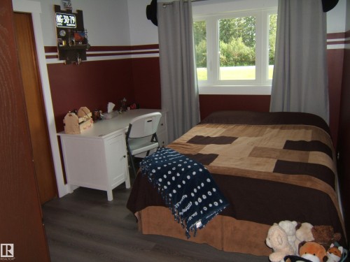 Bedroom featuring wood-finish flooring, a bright window, and a decorative two-tone wall treatment - 151042 Twp  Rd 562, Rural Two Hills County, AB - Indoor Photo Showing Bedroom