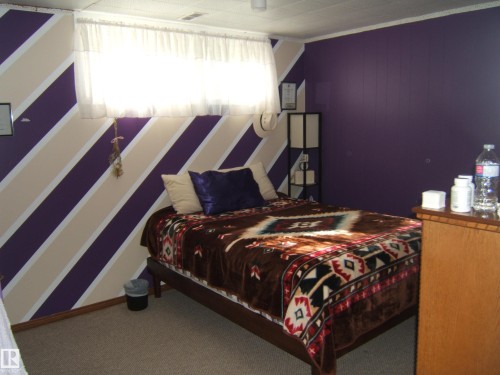 Carpeted room featuring a window with white curtains, a paneled accent wall, and a built-in light fixture - 151042 Twp  Rd 562, Rural Two Hills County, AB - Indoor Photo Showing Bedroom