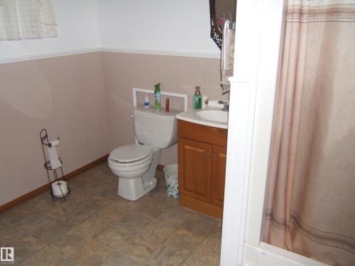 Bathroom featuring a white toilet, wood-finish vanity with an integrated sink, and a shower/tub combination - 151042 Twp  Rd 562, Rural Two Hills County, AB - Indoor Photo Showing Bathroom