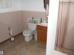 Bathroom featuring a white toilet, wood-finish vanity with an integrated sink, and a shower/tub combination - 