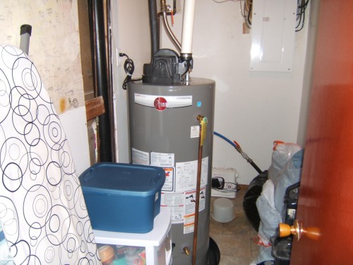 Utility area featuring a water heater, electrical service panel, and tile flooring - 151042 Twp  Rd 562, Rural Two Hills County, AB - Indoor Photo Showing Basement