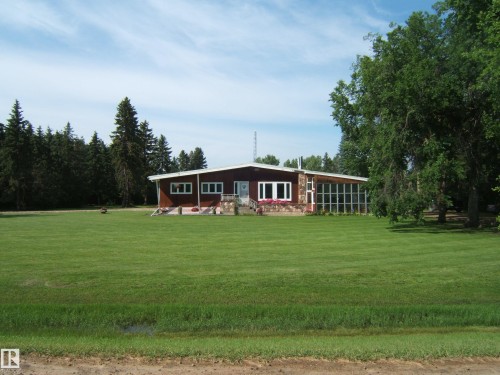 Single-story residence featuring a dark red exterior, stone facade accents, and white trim - 151042 Twp  Rd 562, Rural Two Hills County, AB - Outdoor