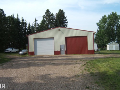 Metal outbuilding with a two-tone facade featuring red and off-white panels, a red roof trim, and a gravel driveway - 151042 Twp  Rd 562, Rural Two Hills County, AB - Outdoor