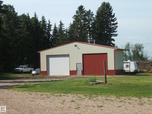 Metal construction outbuilding featuring two large garage doors, a pedestrian entrance, and a gravel driveway - 151042 Twp  Rd 562, Rural Two Hills County, AB - Outdoor