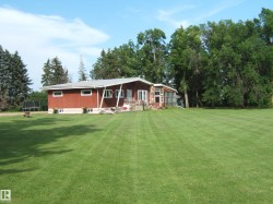 Expansive green lawn bordering a one-story residence with red siding and a stone facade section - 