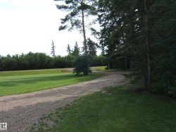 Extensive gravel driveway bordered by lush green lawns - 