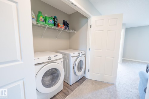 Dedicated laundry area featuring wood-finish flooring, overhead wire shelving, and light gray wall paint - 5403 Lark Landing Nw, Edmonton, AB - Indoor Photo Showing Laundry Room