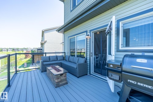 Upper-level deck featuring composite decking, glass panel railing, and a built-in fire pit - 5403 Lark Landing Nw, Edmonton, AB - Outdoor With Deck Patio Veranda With Exterior