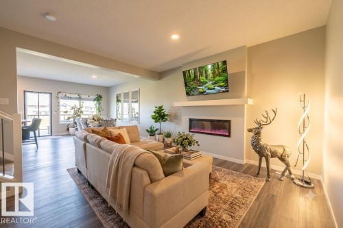 Living area featuring wood-finish flooring and a built-in electric fireplace with a mantel - 5403 Lark Landing Nw, Edmonton, AB - Indoor Photo Showing Living Room With Fireplace