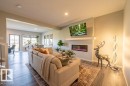 Living area featuring wood-finish flooring and a built-in electric fireplace with a mantel - 5403 Lark Landing Nw, Edmonton, AB  - Indoor Photo Showing Living Room With Fireplace 
