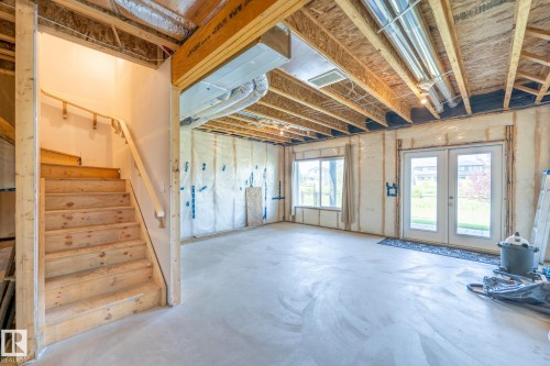 Unfinished lower level featuring an exposed ceiling, concrete flooring, and a wooden staircase - 5403 Lark Landing Nw, Edmonton, AB - Indoor Photo Showing Other Room