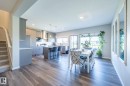 Open-concept living area featuring wood-finish flooring, a contemporary kitchen with stainless steel appliances, a kitchen island with seating, recessed lighting, and a dining area with a large window - 5403 Lark Landing Nw, Edmonton, AB  - Indoor Photo Showing Dining Room 