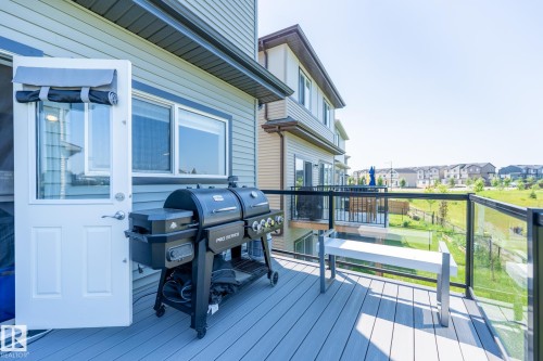 Deck featuring composite decking, clear glass panel railing with a black frame, and a white bench - 5403 Lark Landing Nw, Edmonton, AB - Outdoor With Exterior