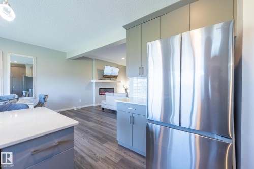 Stainless steel French door refrigerator with integrated cabinetry, white subway tile backsplash, and light-toned countertops - 5403 Lark Landing Nw, Edmonton, AB - Indoor Photo Showing Kitchen