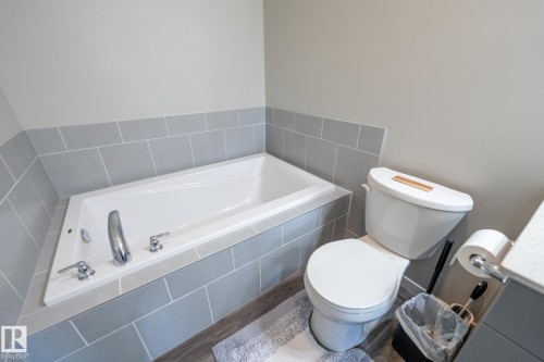 Built-in bathtub featuring a chrome faucet and gray tile surround - 5403 Lark Landing Nw, Edmonton, AB - Indoor Photo Showing Bathroom