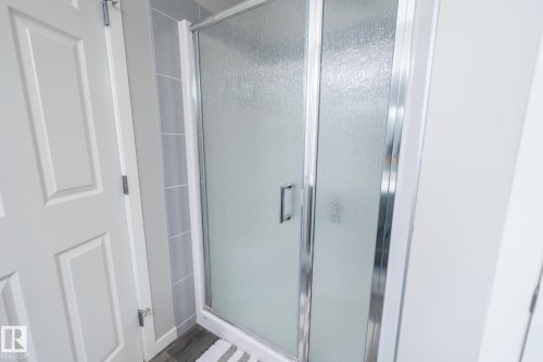 Shower enclosure featuring frosted glass panels and chrome framing - 5403 Lark Landing Nw, Edmonton, AB - Indoor Photo Showing Bathroom