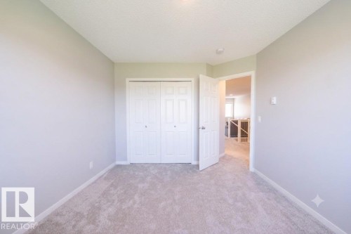 Neutral-toned room featuring a soft carpet, baseboard trim, and a bi-fold closet - 5403 Lark Landing Nw, Edmonton, AB - Indoor