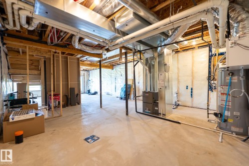 Unfinished basement with exposed wood framing, concrete floor, visible ductwork, and essential mechanical systems including a water heater and furnace - 5403 Lark Landing Nw, Edmonton, AB - Indoor Photo Showing Basement