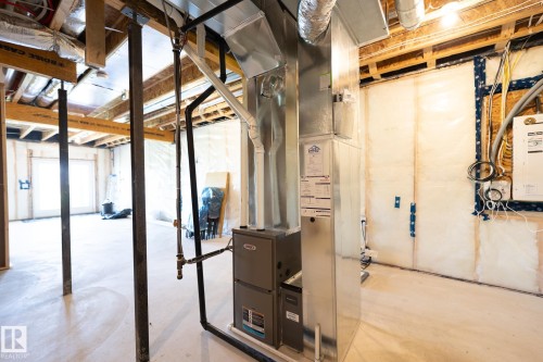 Unfinished basement space featuring a central HVAC unit, exposed ceiling joists, support beams, and a concrete floor - 5403 Lark Landing Nw, Edmonton, AB - Indoor Photo Showing Basement