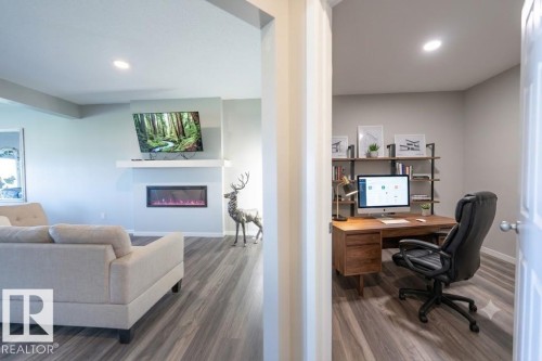 Living area featuring an electric fireplace with a white mantel, recessed lighting, and wood-finish flooring - 5403 Lark Landing Nw, Edmonton, AB - Indoor With Fireplace