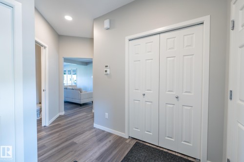 Entryway featuring wood-finish flooring, recessed lighting, white six-panel bifold closet doors, and light gray wall paint - 5403 Lark Landing Nw, Edmonton, AB - Indoor Photo Showing Other Room