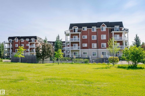 Multi-story residential buildings with red siding and white trim - #205 226 Macewan Rd Sw, Edmonton, AB - Outdoor With Balcony With Facade