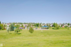 Green space featuring a playground, open field, and covered picnic structure - 