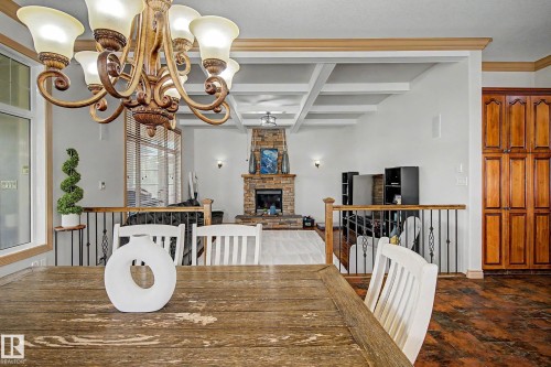 Open-concept living space featuring a stone-clad fireplace, coffered ceiling, and rich wood-finish flooring - 38 Longview Point(E), Spruce Grove, AB - Indoor Photo Showing Dining Room